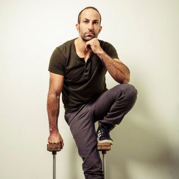 Portrait de Karim Randé, assis, un genou relevé.
