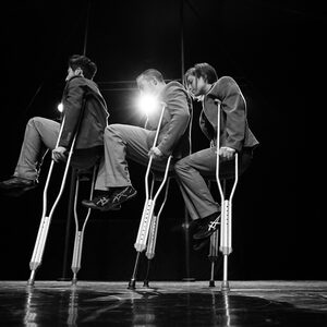 Deux artistes sur béquilles à contre-jour, silhouettes découpées par la lumière.