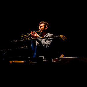 Un musicien allongé joue dans la pénombre.